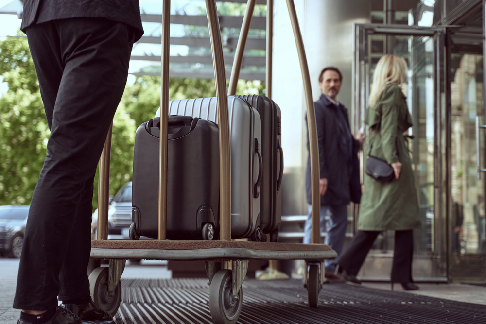 Couple,Of,Hotel,Guests,Entering,A,Hotel,While,Looking,Back Employee Benefits Hospitality Industry